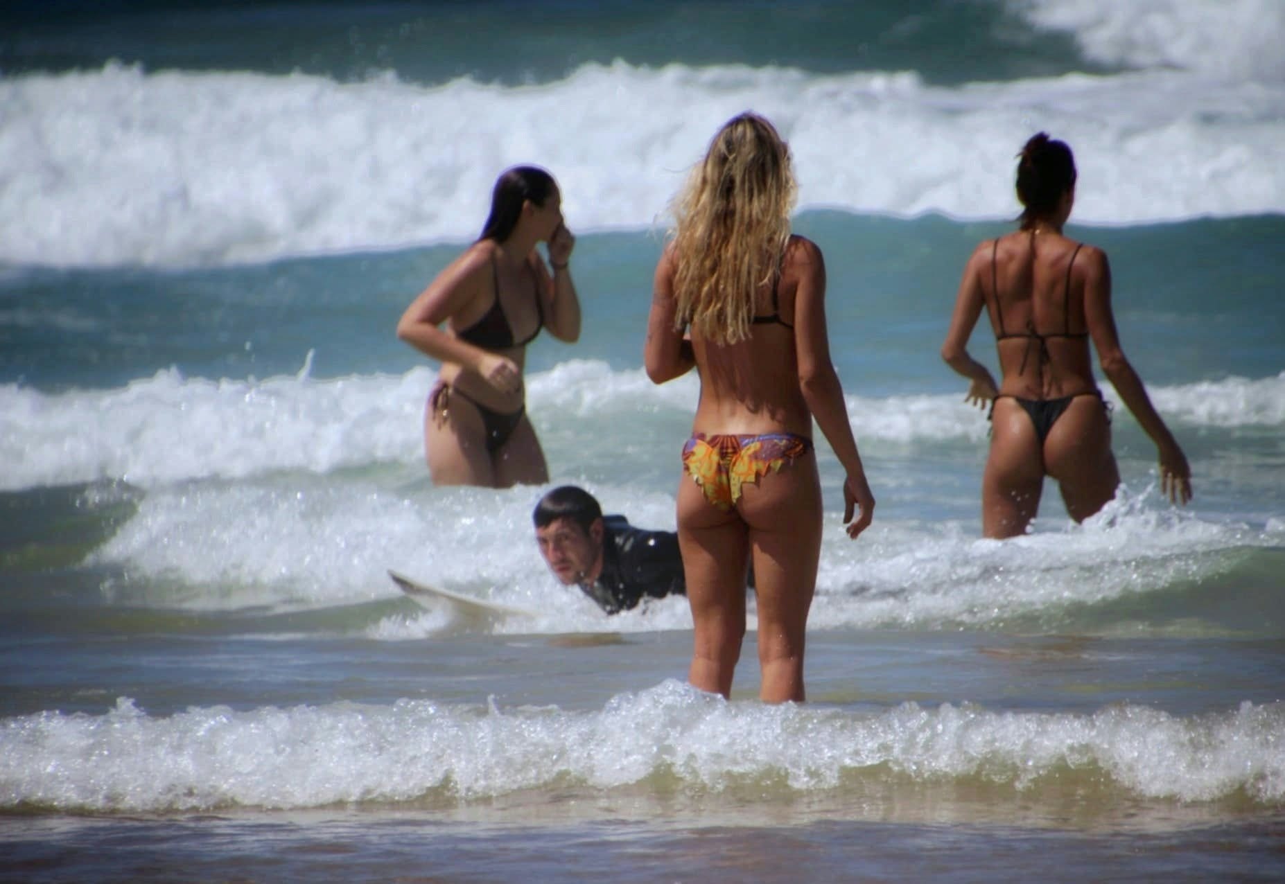 Scène de plage avec baigneuses et surfeur